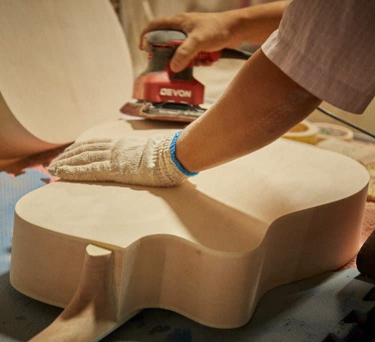 Un trabajador fabricando una guitarra con herramientas y accesorios completos para trabajar la madera