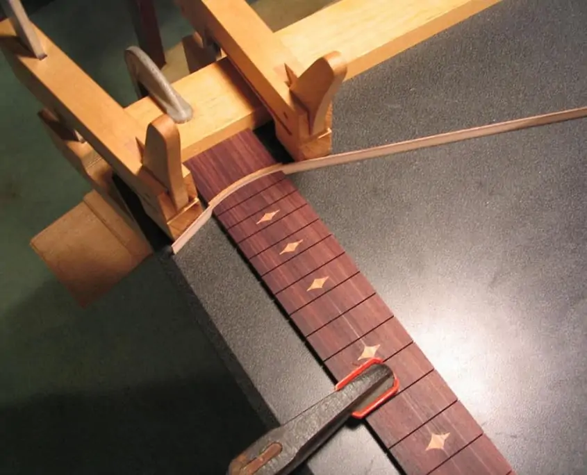 The neck and fretboard of the guitar being finalized using a unique type of wood